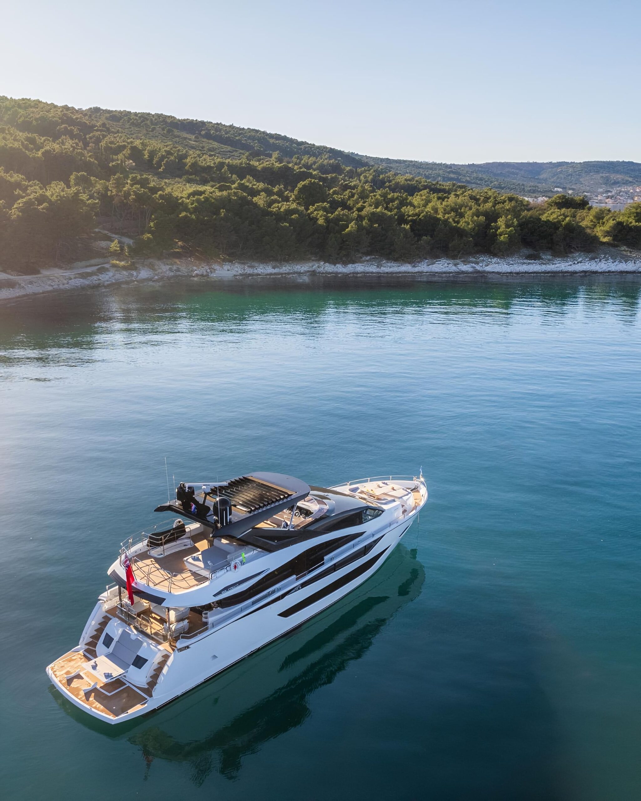 white,yacht,rests,near,forested,coast,,sun,deck,and,clear